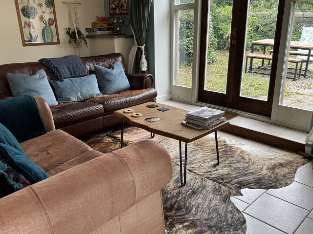 Comfortable lounge at The Coach House holiday cottage with leather sofas, patio doors and garden views in West Wales.
